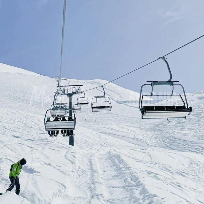 A snowy trail atop a mountain with cable cars in Albania.